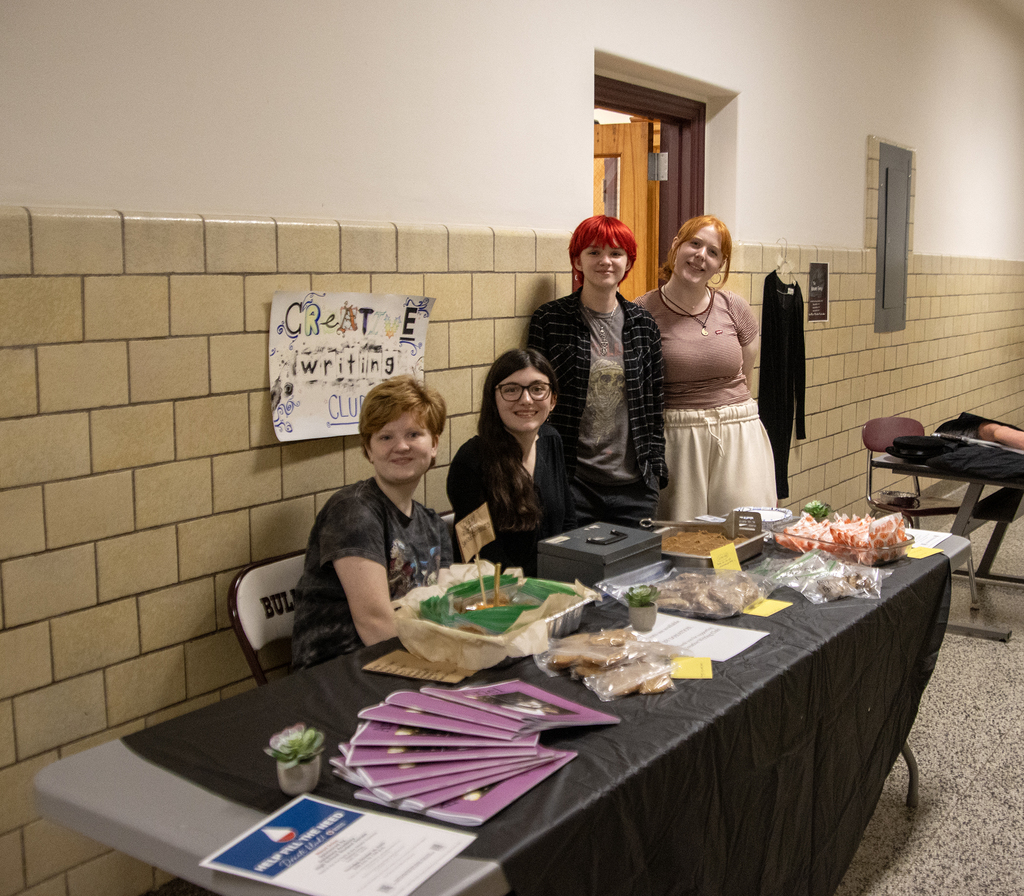 4 students staff a bake sale table promoting drama club