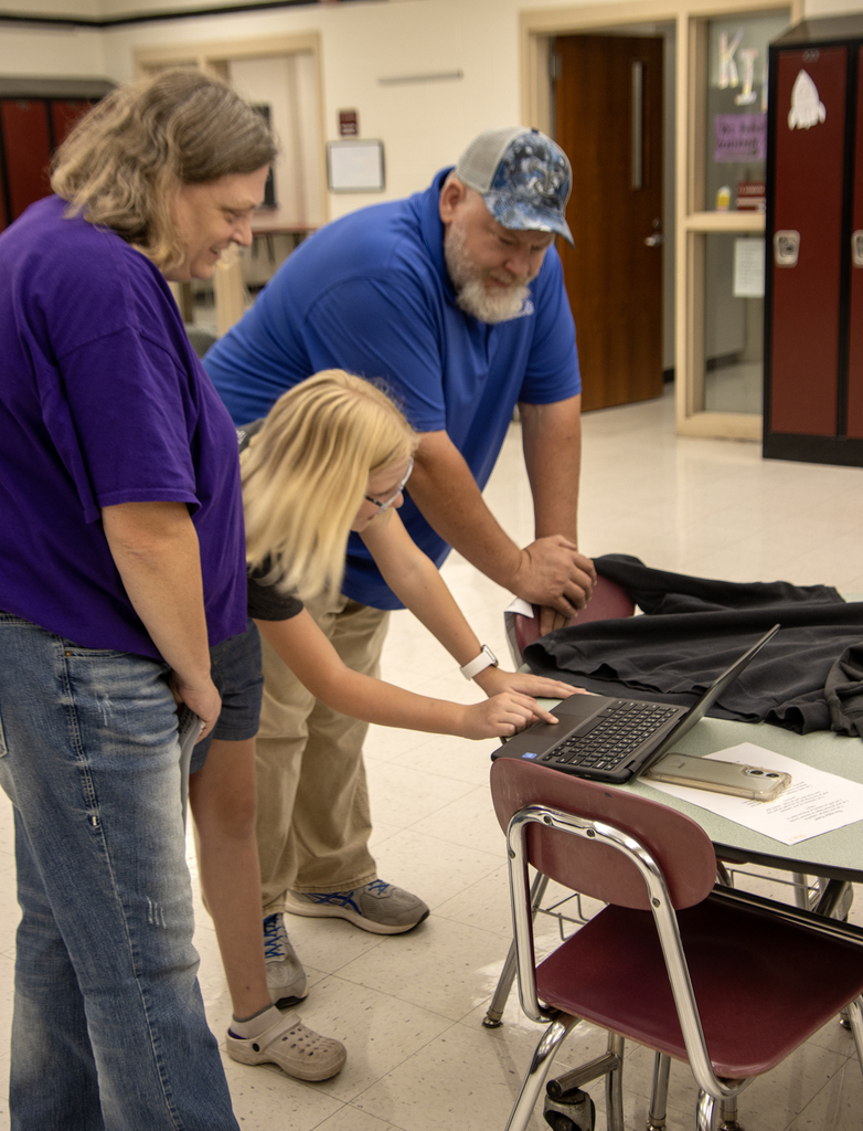 2 adults and a middle school student look at a laptop computer