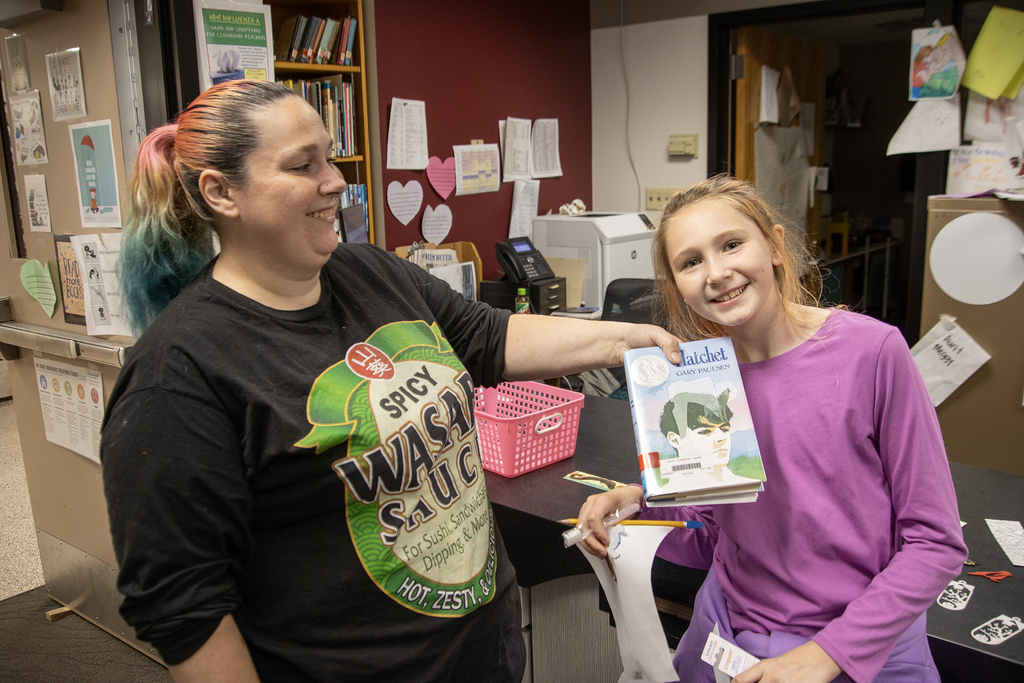 mother and daughter holding book in library