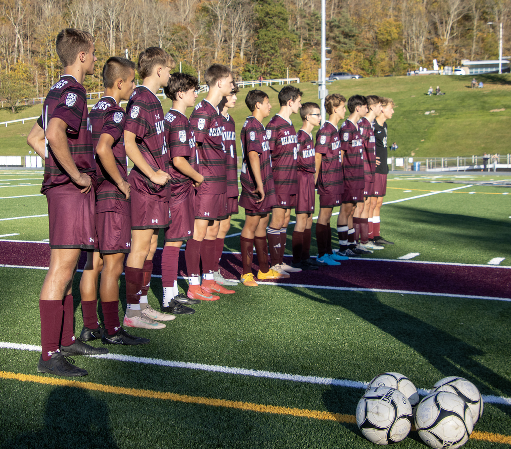 soccer players stand in row on field