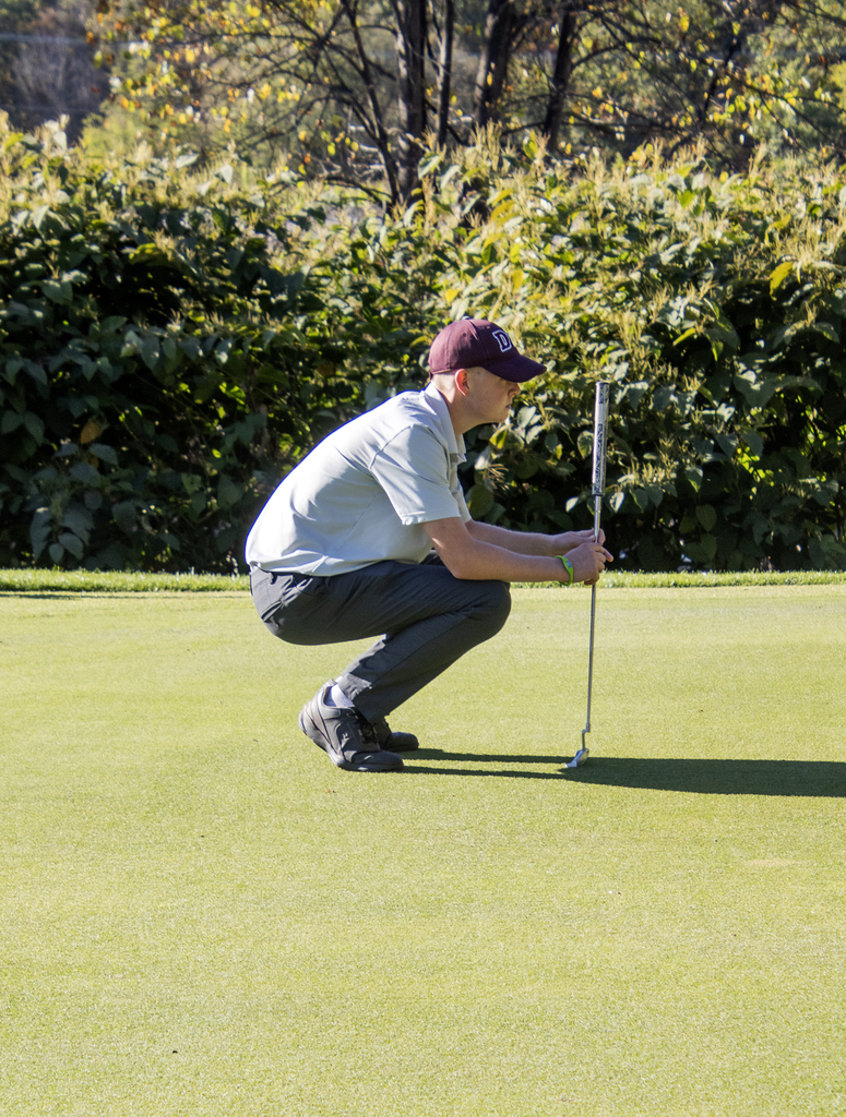 golfer squats to line up shot