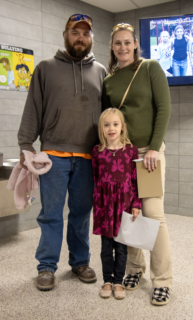 child poses with parents in lobby