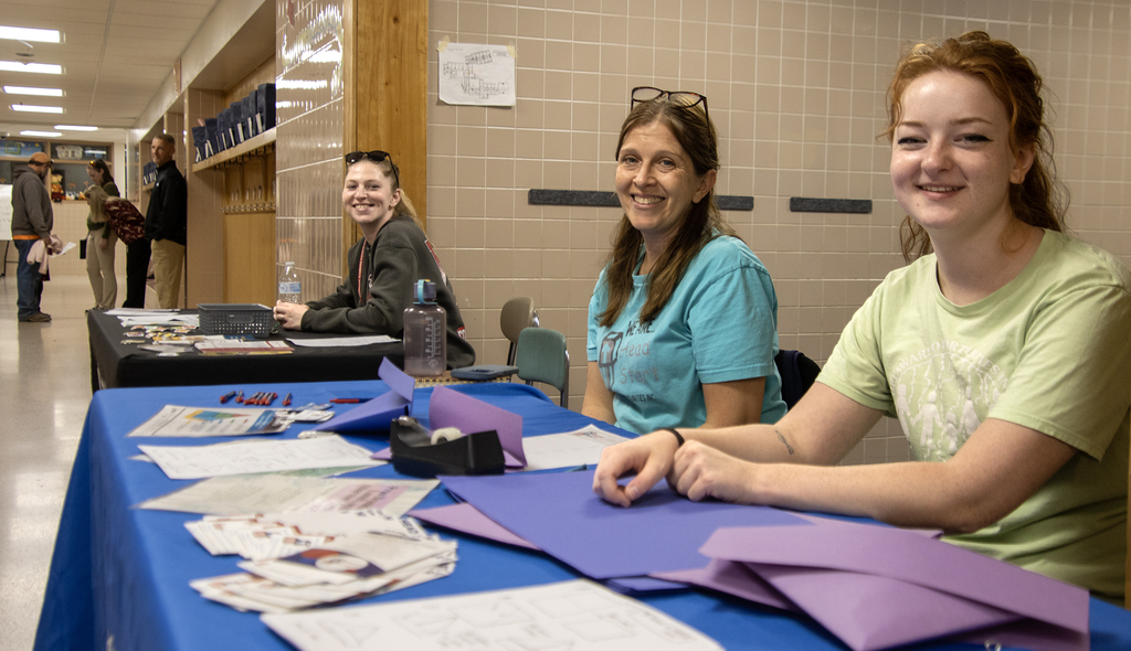 3 organization representatives smile at their tables