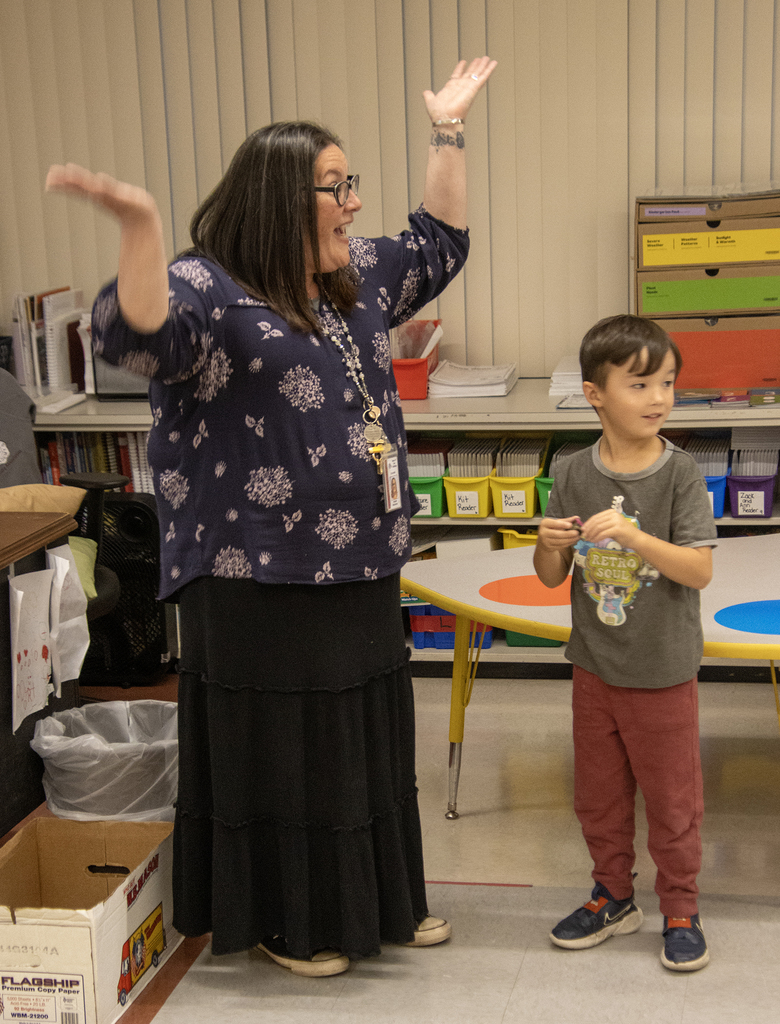 teacher throws up hands while child looks at something