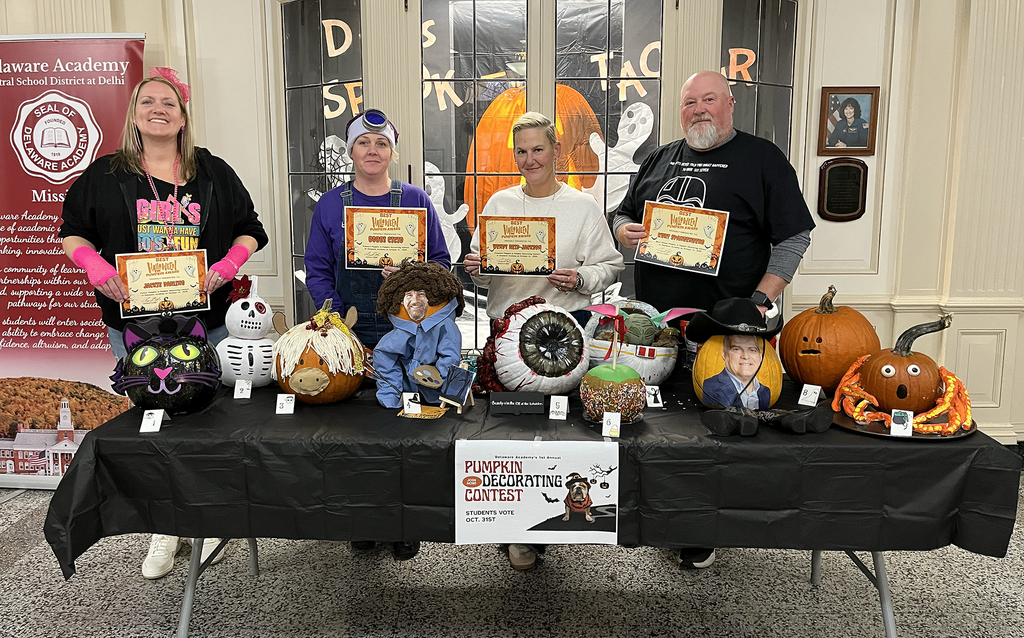 4 adults stand with certificates, behind table of decorated pumpkins
