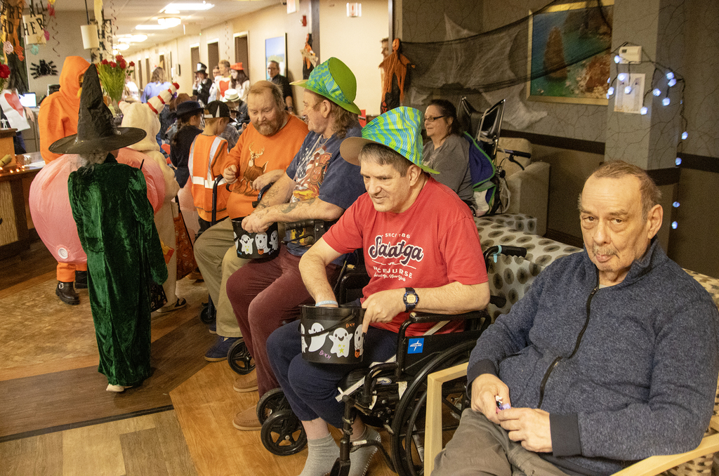 2nd grade students in costume visit with residents of nursing home, who hand out candy