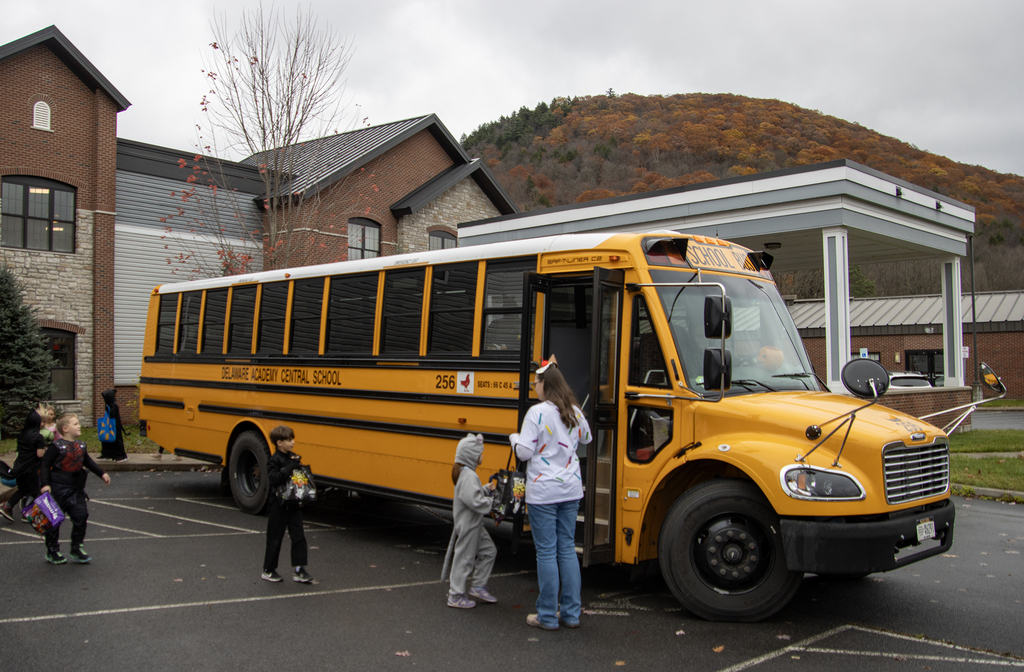 2nd grade students in costume leave the nursing home and get on the school bus