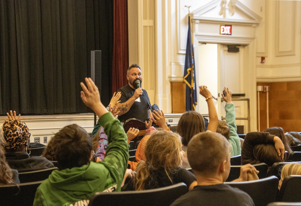 Students raise their hands listening to Jared Campbell