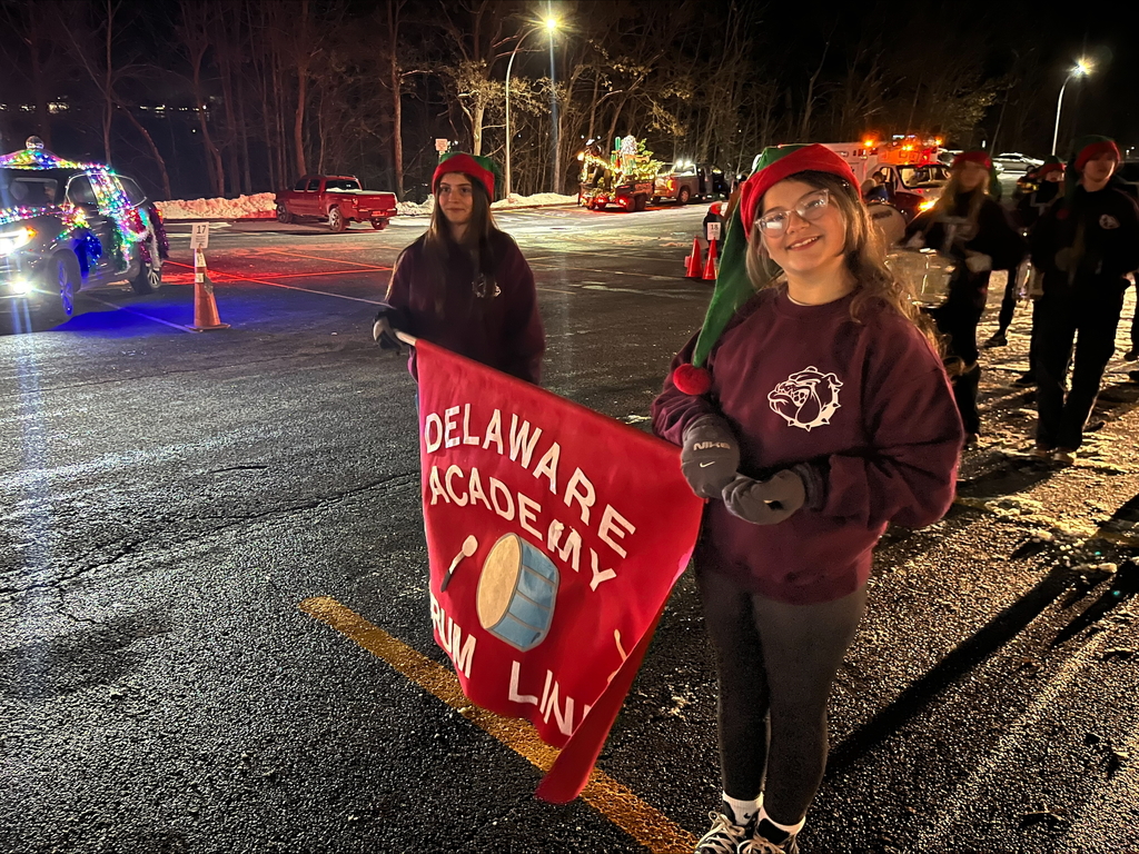 students in elf hats holding drum line banner