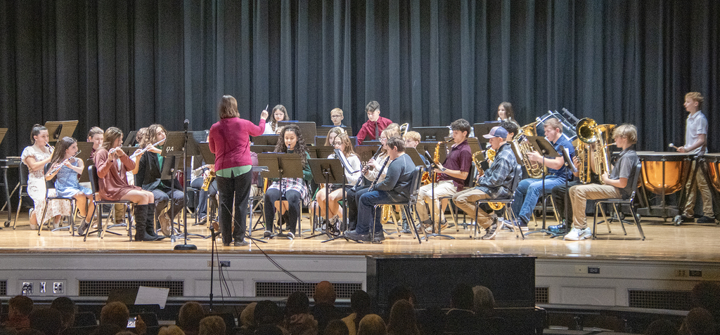 director conducting middle school band on stage