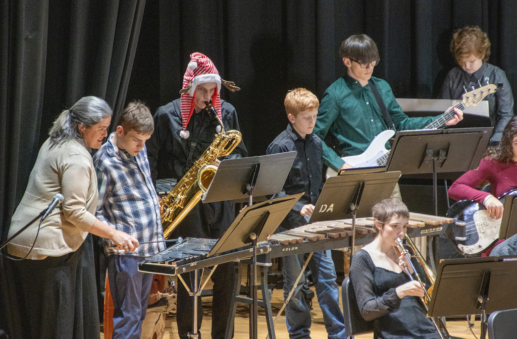 students play on stage in jazz band, one student assisted by an aide