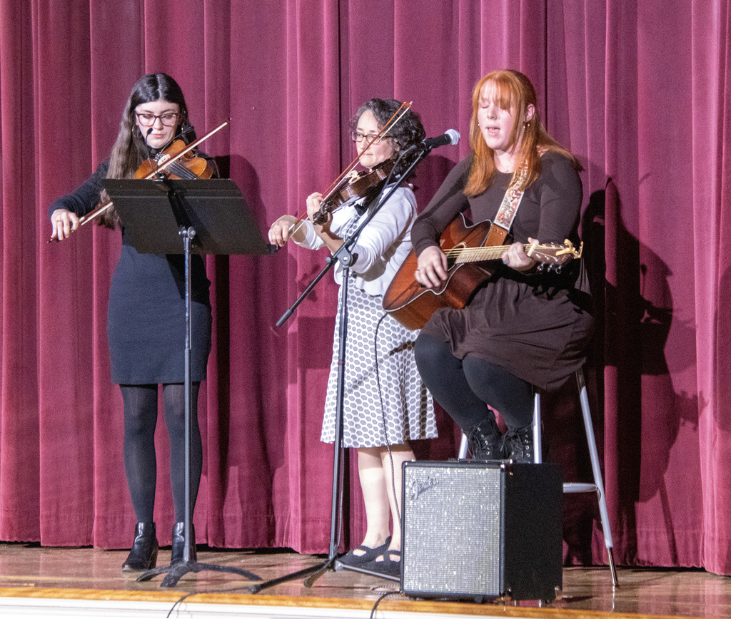 Briannah Pringle sings and plays guitar, accompanied by 2 violinists