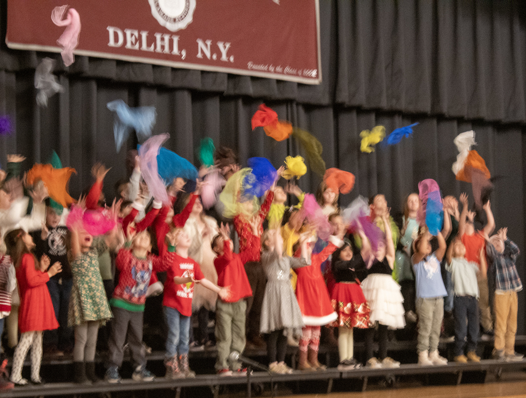 students swing colorful scarves as they sing