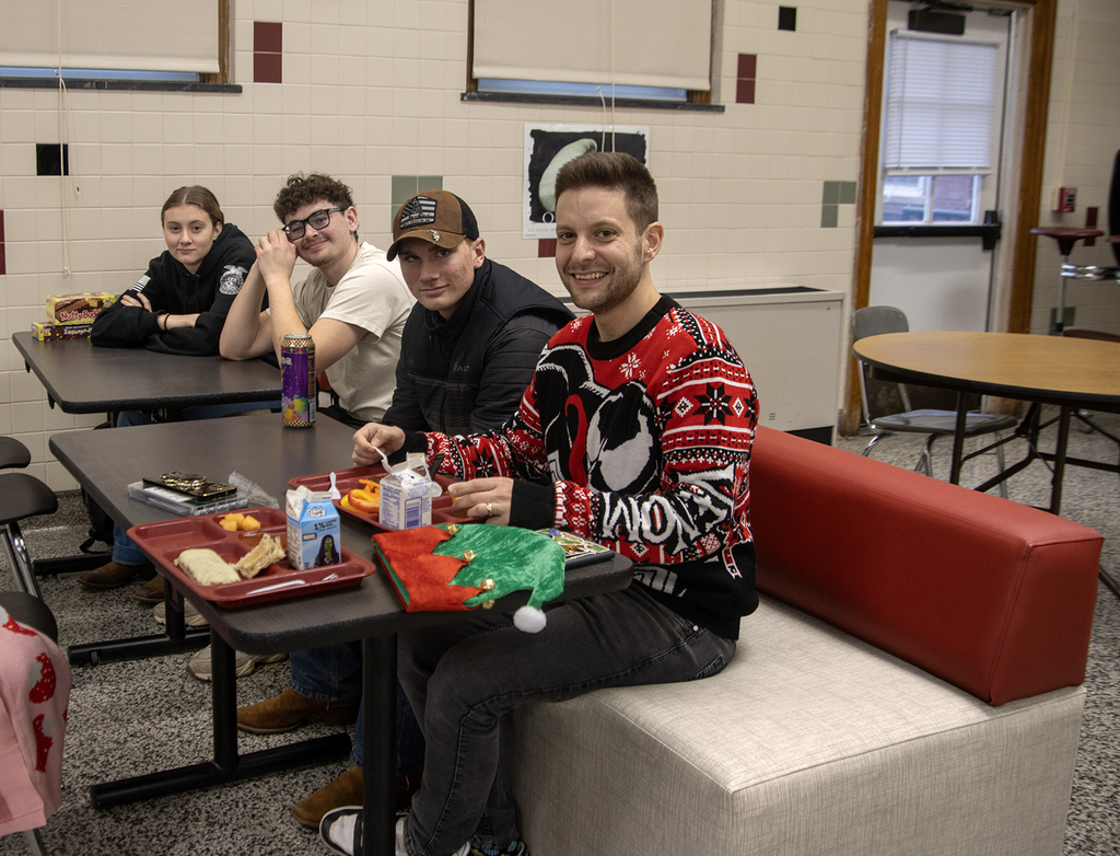 teacher and 3 students sitting on new seats in cafeteria