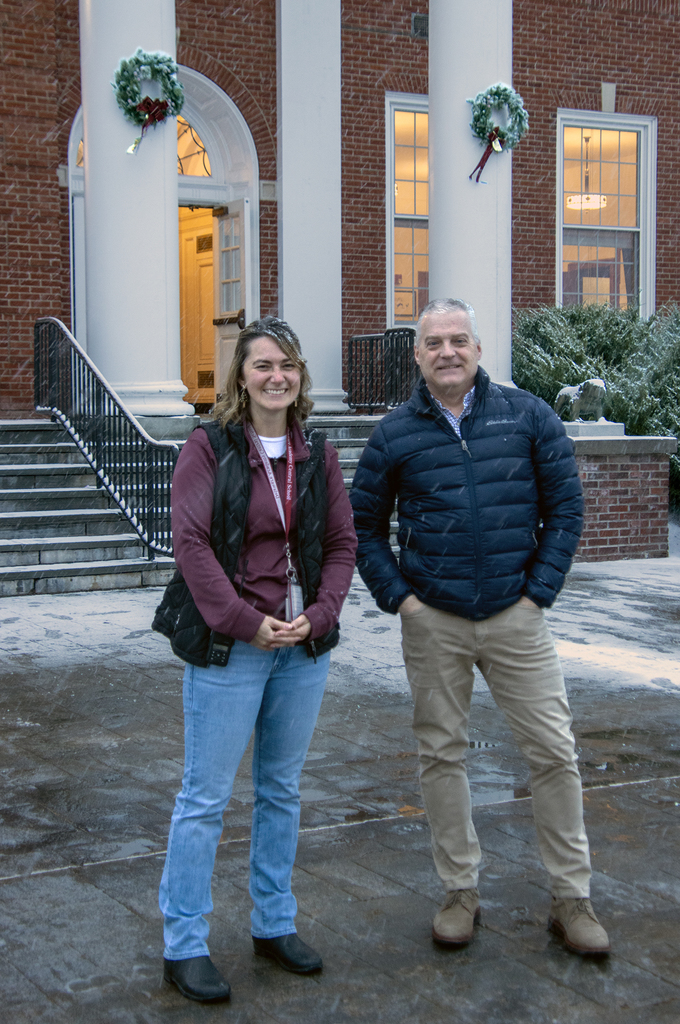 Ms. Trask and Mr. Shultz in front of school, showing wreaths on building