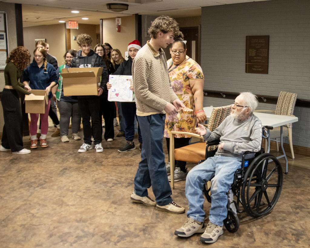 student hands resident an ornament as other students and staffer watch