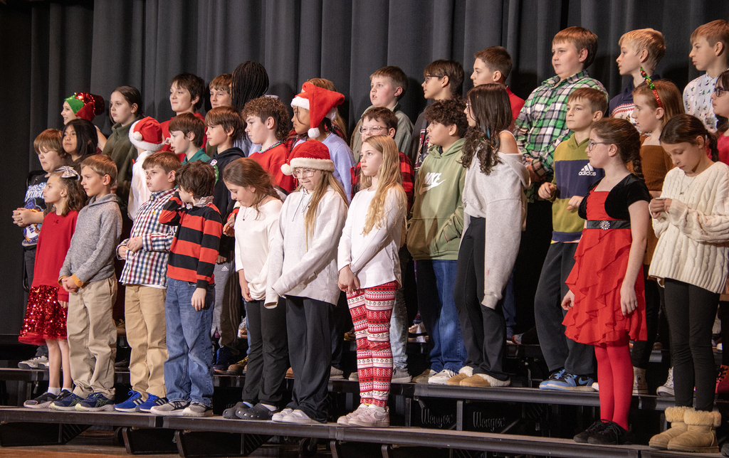 students smile and sing on stage