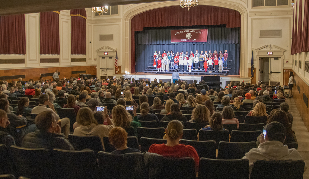 view from back of crowded auditorium with students on stage