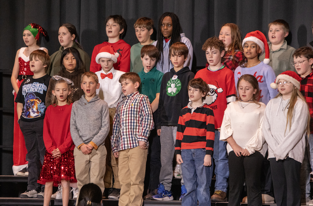 students smile and sing on stage