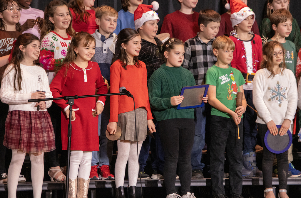 students smile and sing on stage