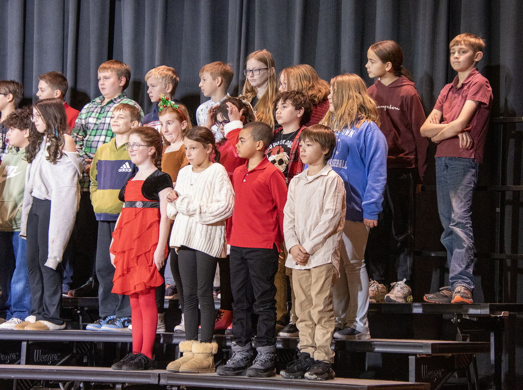 students smile and sing on stage