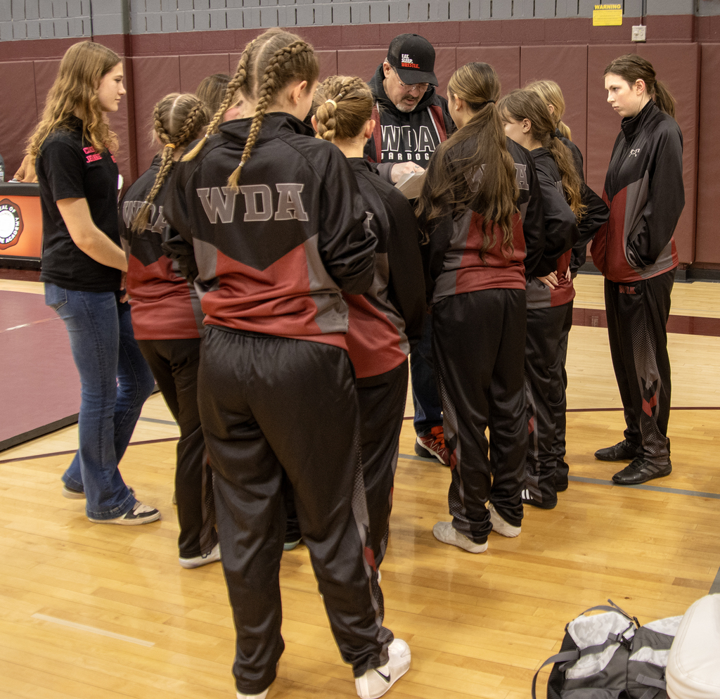 girls wrestling team gathers around coach