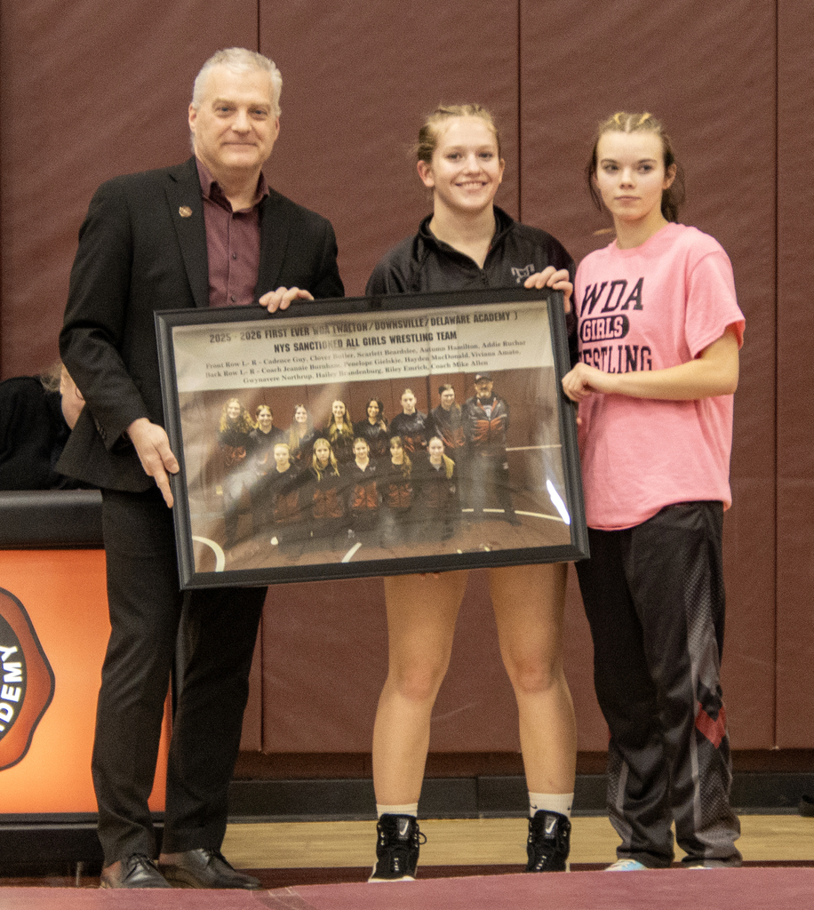 Mr. Shultz accepts a framed photo of the girls wrestling team from team captains