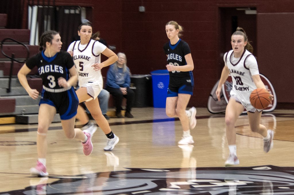player dribbling the ball, 3 others run near her