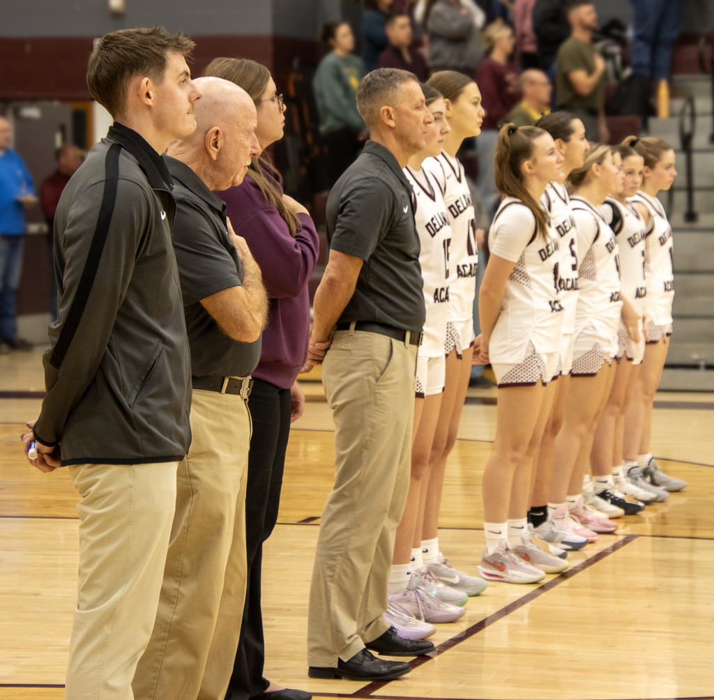 basketball team stand in line for national anthem (viewed from side)