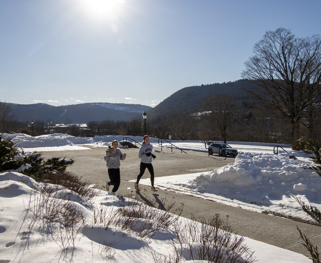 2 students running outside on sunny winter day