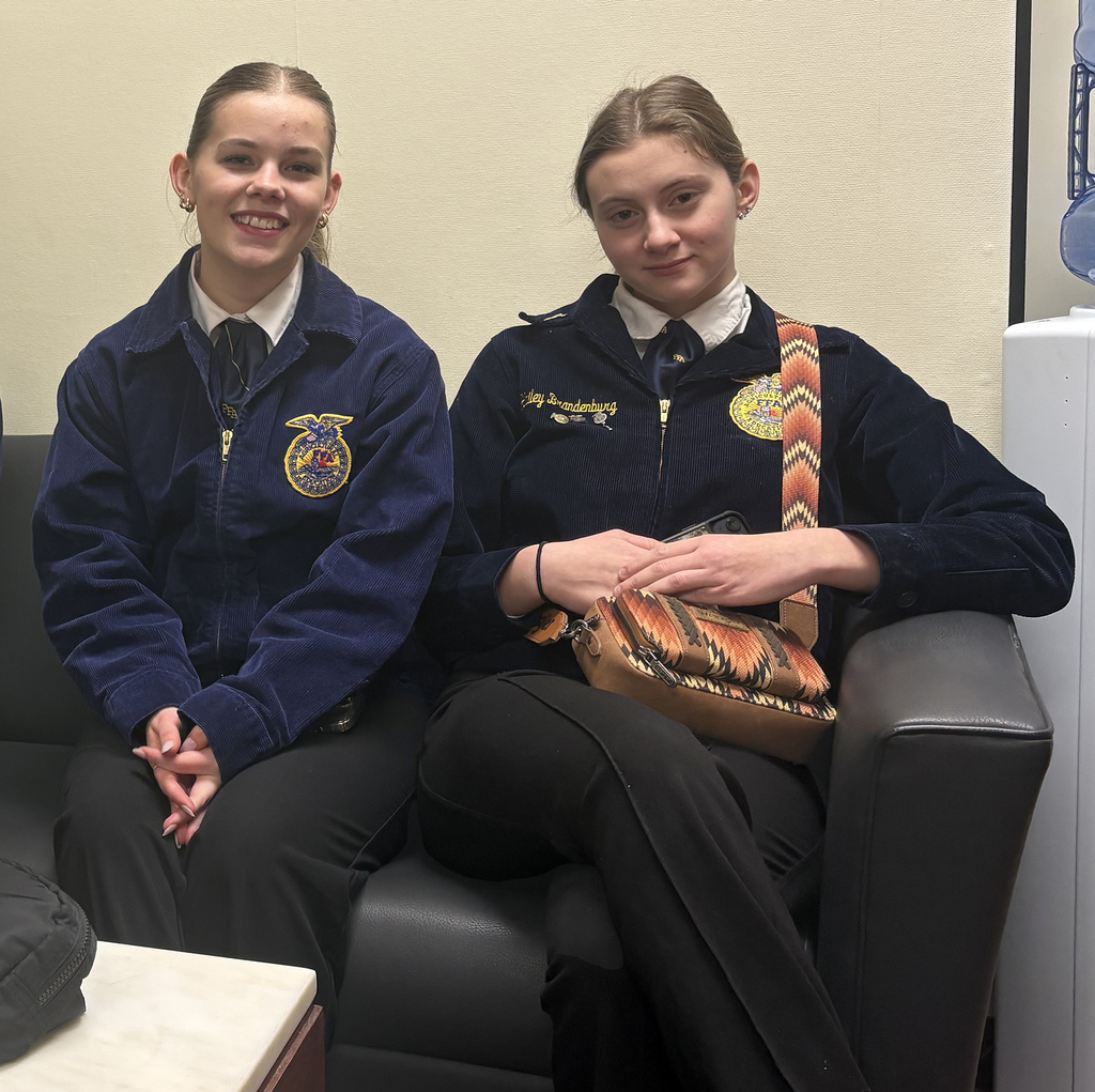 students Delaney McCann and Hailey Brandenburg pose wearing FFA jackets