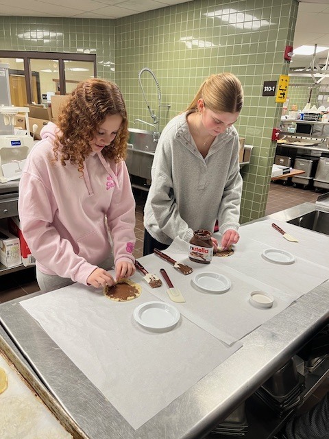 2 students making food in culinary lab