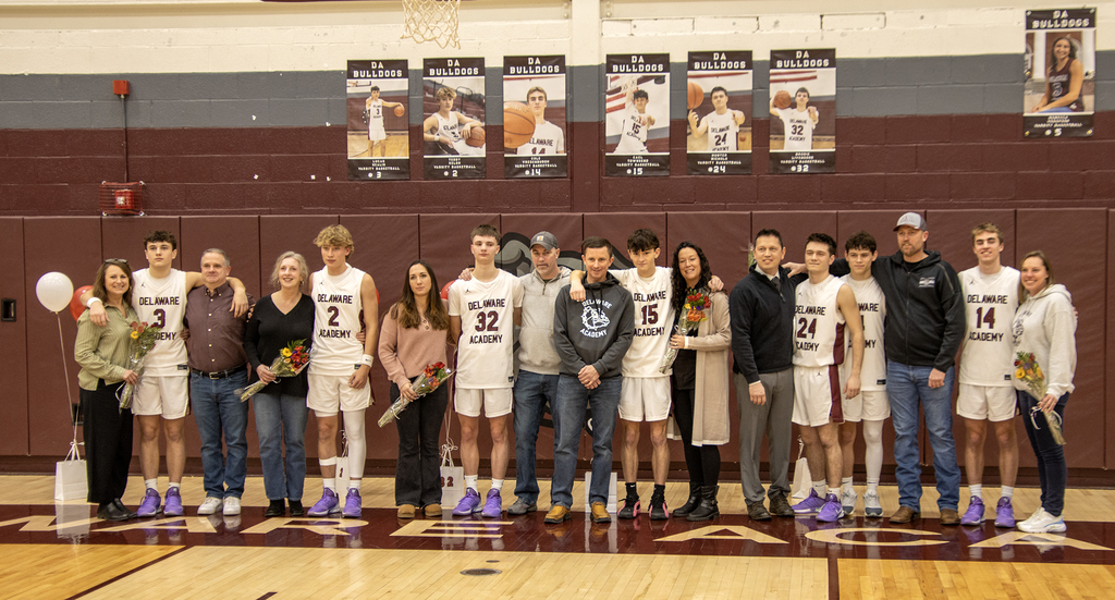 6 seniors pose wqith family members on the gym floor