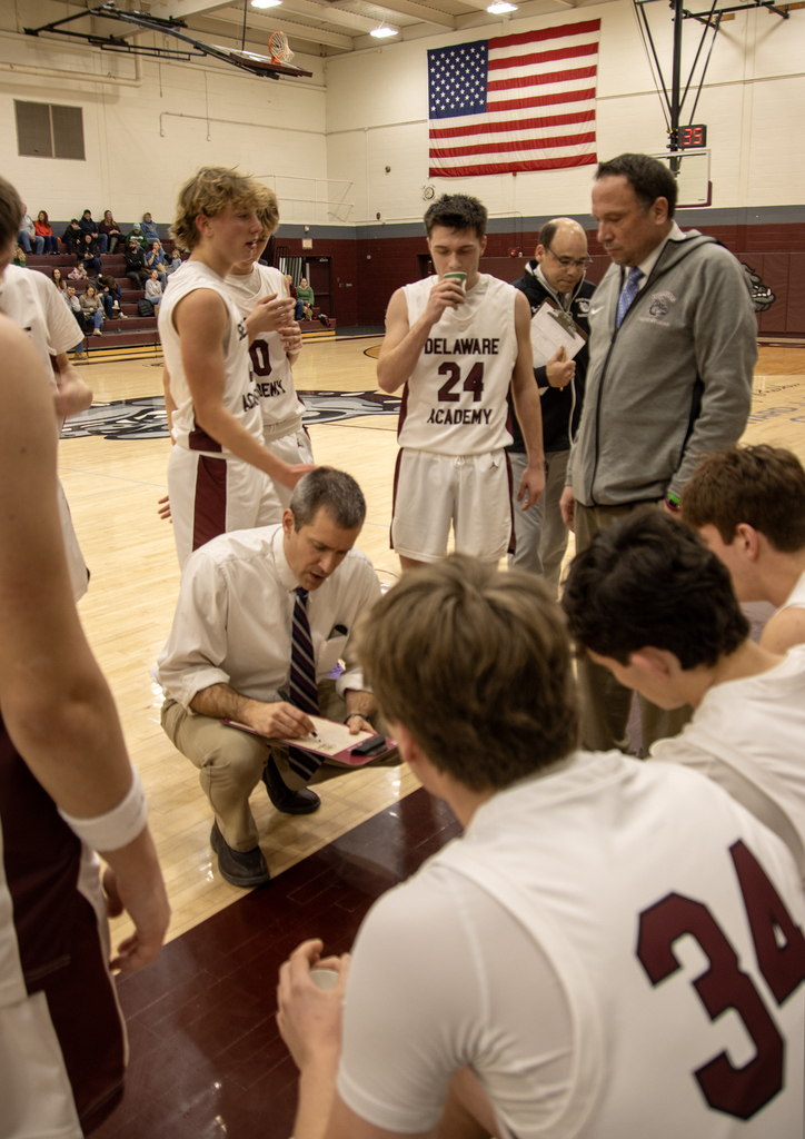 coach huddles with boys basketball team