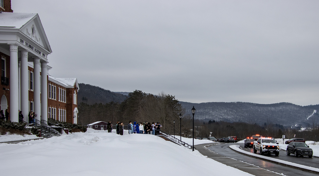 staff and students gathered in front of school as convoy of emergency vehicles pass by