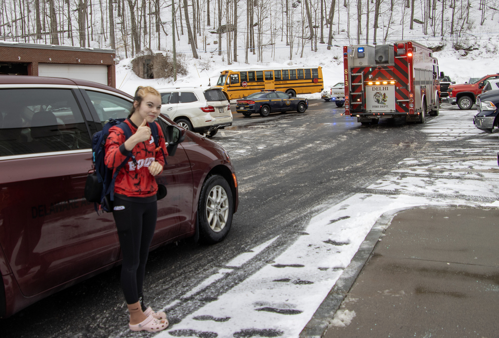 Cadence gives a thumbs up before entering car; police and fire trucks are waiting in the background