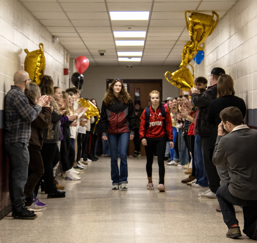 Coach and Cadence Guy walk down hall bein cheered by students