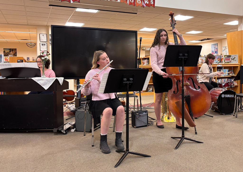 two students on flute and bass, accompanied by two music teachers on piano and drums