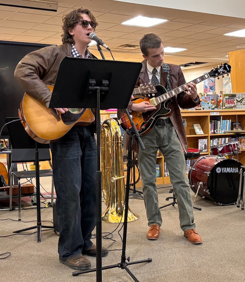 two students singing and playing guitars