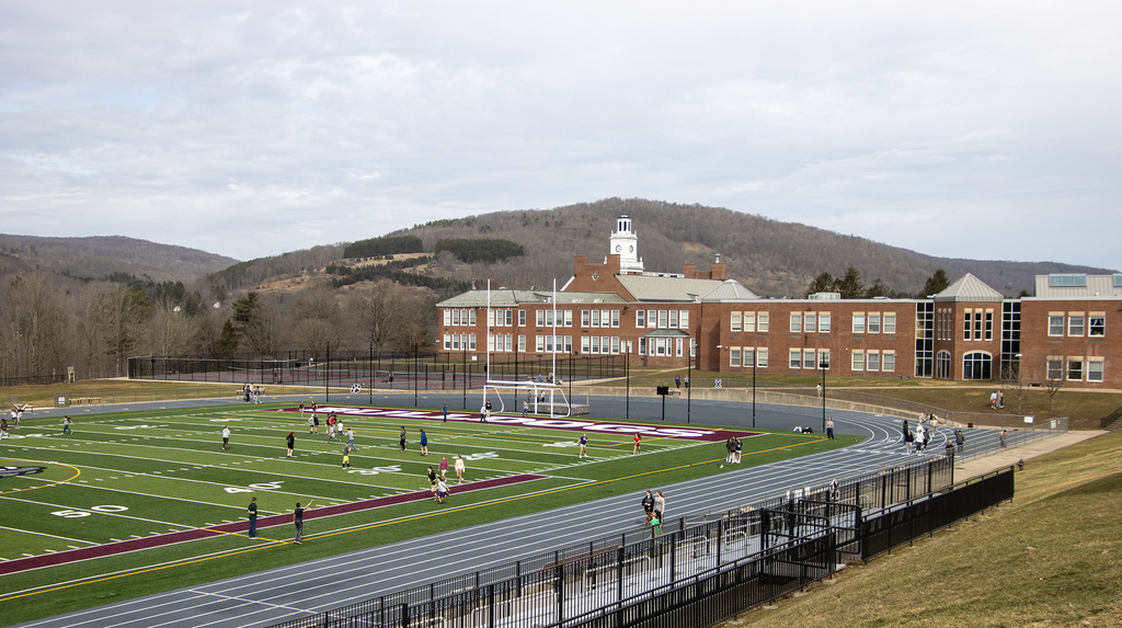 view of middle school children playing on the athletic field with the school in the background