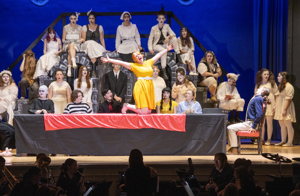 Brianna Pringle singing on stage, surrounded by many cast members