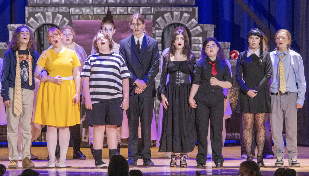 10 cast members singing on stage