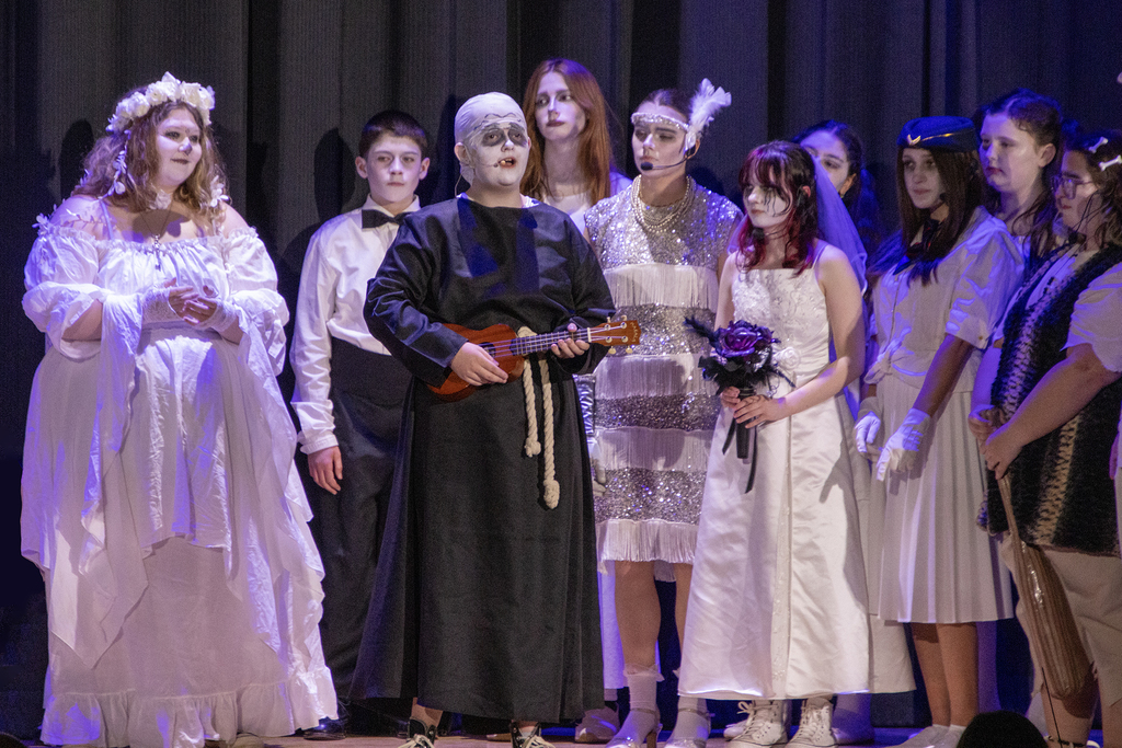 Uncle Fester singing, surrounded by cast members