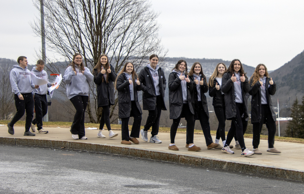 the girls varsity basketball team gives thumbs up signs on sidewalk
