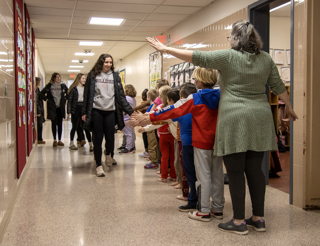 girls basketball team is greeted by first grade students in hallway