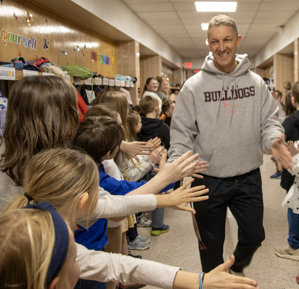 elementary students high-five Coach Bruce