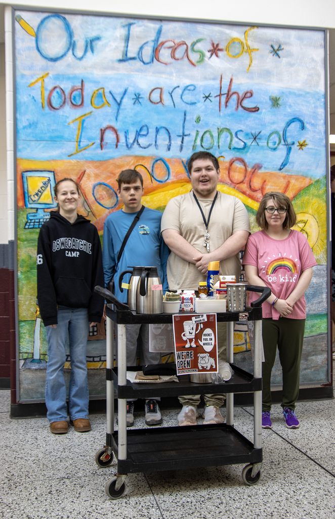 four students with a coffee wagon