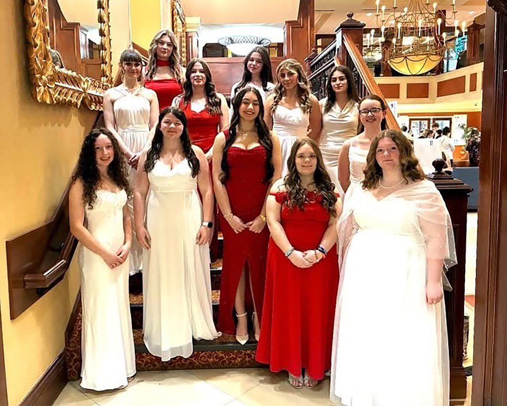 12 FCCLA students in ball gowns pose for a group picture