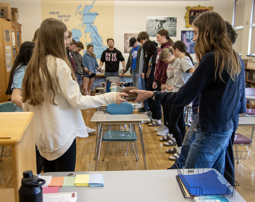 Students participate in an activity with Sweethearts & Heroes, incolving a cirlce and a toy football.