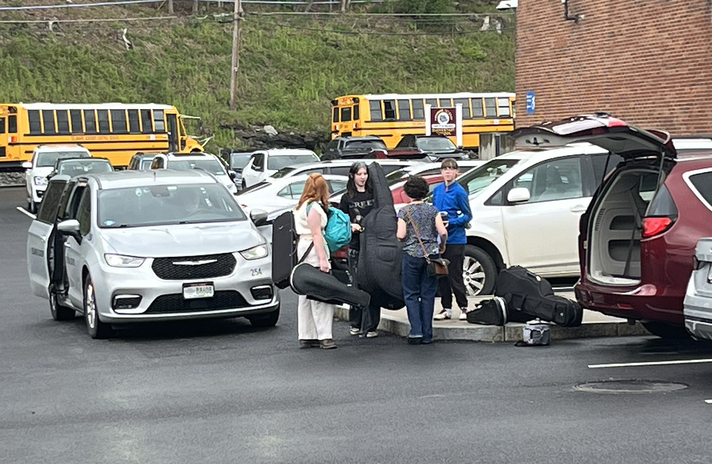 Mrs. Gibson and 3 students loading instruments into vans.